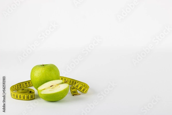 Fototapeta Green apple rolled up in measuring tape, symbolizing healthy life