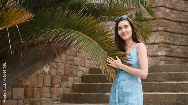 Obraz A young girl touches a palm leaf. Travel and vacation