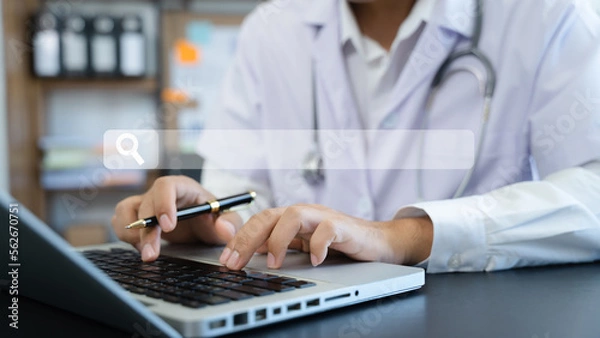 Fototapeta Male doctor working on desk with laptop computer and paperwork in the office. Medical and doctor concept.