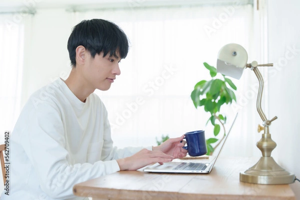 Obraz 飲み物を片手にパソコンを操作する男性