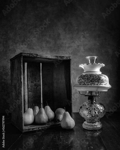 Fototapeta Collection of Yellow and Green Pears arranged in an Antique Wooden Apple Box lit by an Antique Hurricane Lamp
