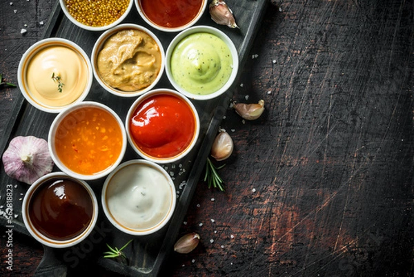 Fototapeta Different types of sauces in bowls on a cutting Board with garlic.