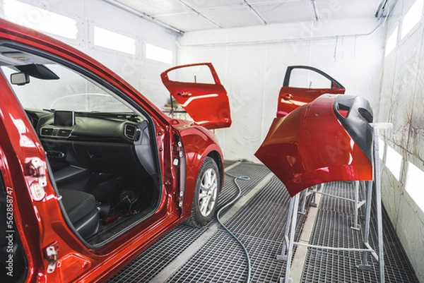 Fototapeta A luxury red car in a paint shop with its doors removed for a fresh coat of paint. High-quality photo