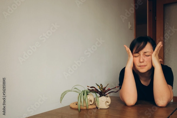 Fototapeta tired mom alone in the kitchen with a headache sitting at the table in silence