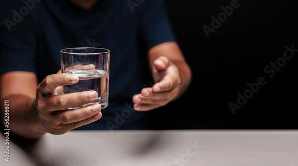 Obraz Man's hand holding a glass of clean water and making a gesture inviting clean water.