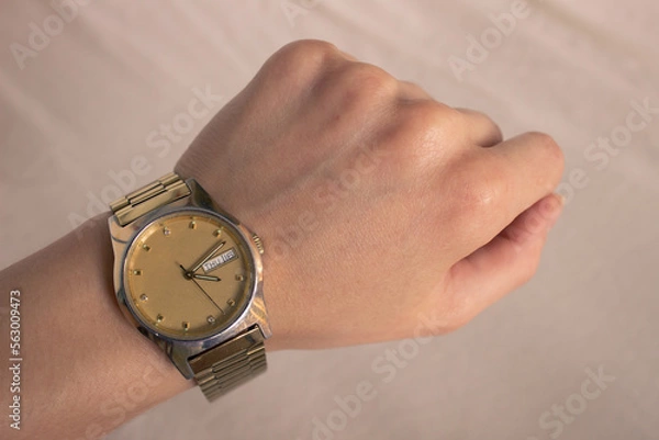 Obraz Classic Gold Watch on wrist. Woman watching watch in wrist watch on a light background. First-person view (FPV), first-person point of view (POV)