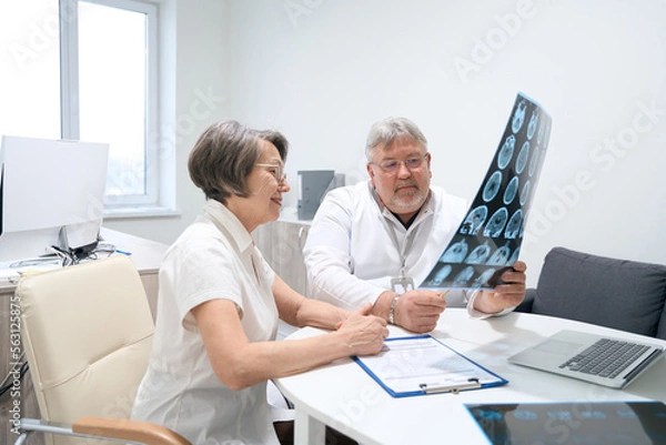 Obraz Elderly doctor and patient are studying MRI scans
