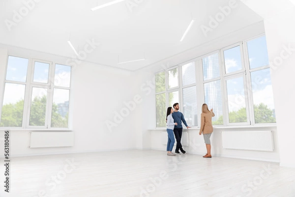 Fototapeta Real estate agent showing new apartment to couple