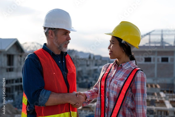 Fototapeta Construction engineer making handshake with foreman, smiling face at real estate site background, agreement successful to work together to develop landscape and utilities in property project.