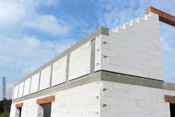 Fototapeta A reinforced concrete beam and reinforced concrete columns, reinforced brick lintels, a rough door and windows openings, a gable wall, walls made of aac blocks, blue sky in the background