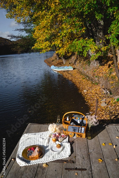 Fototapeta Picnic by the lake during autumn with vibrant foliage and a serene atmosphere