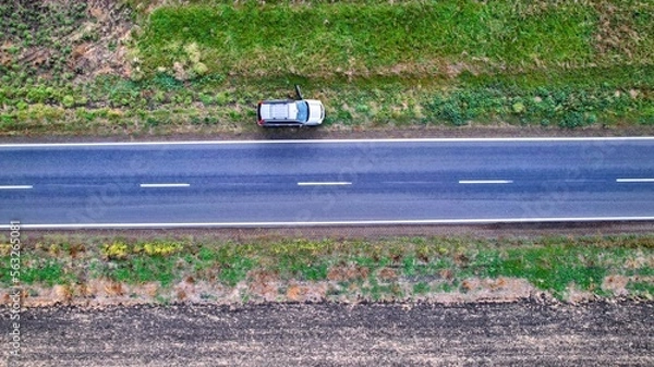 Obraz Top down drone shot of a car on the side of the road