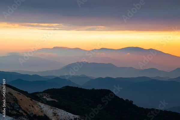 Obraz 日の出に赤く染まった空と山並みのシルエット
