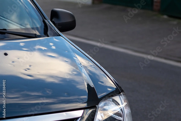 Fototapeta Black car engine hood with many hail damage dents show the forces of nature and the importance of car insurance and replacement value insurance against hail dents of storm hazards extreme weather