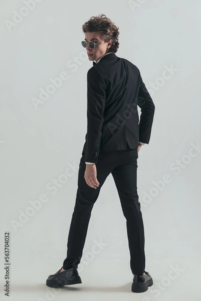 Fototapeta back view of elegant man in tuxedo looking over shoulders