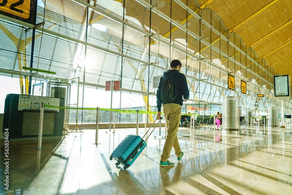 Fototapeta Full length view of unrecognizable man traveling at airport hallway with luggage