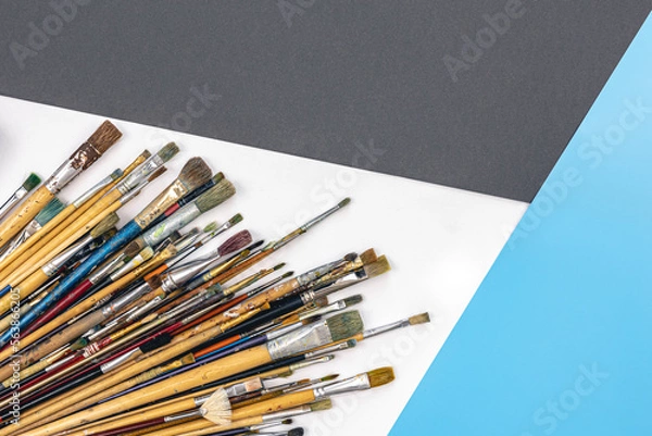 Fototapeta Many brushes for painting on a colored background, top view.