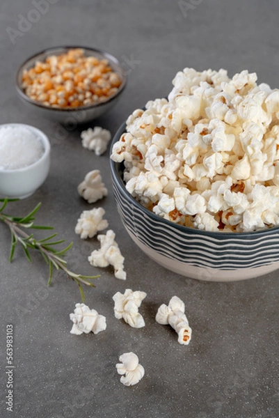 Obraz popcorn in a bowl , salt and popcorn kernels on a gray concrete background, close up and selected focus