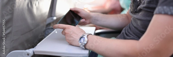 Fototapeta Man hands with a smartphone sits in cabin of airplane or train
