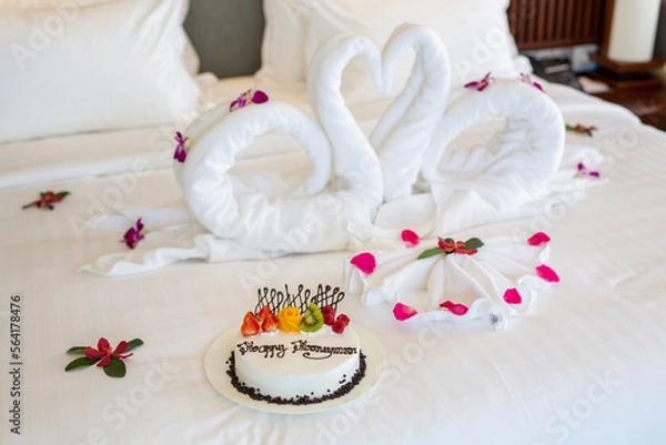 Obraz 행복한 허니문을 축하하기 위해 놓여진 케이크와 수건으로 접은 한쌍의 새