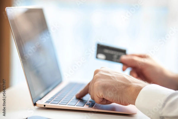 Fototapeta Purchases via the Internet and payment for services buy credit card. Hands type text and enter data on the laptop keyboard. An office worker checks his email while sitting at his desk