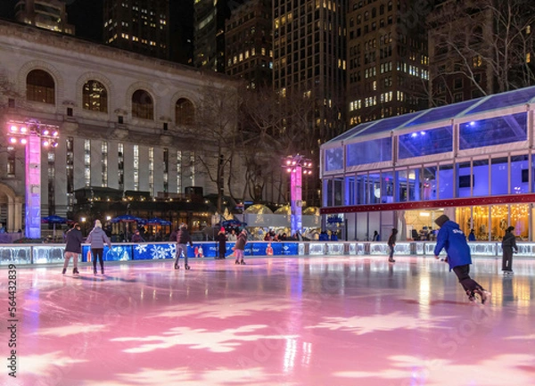 Fototapeta People skating on an outdoor rink in Bryant Park, New York City, at night
