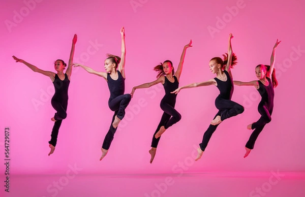 Fototapeta Сhildren dancing. Group of children, little girls in sportive style clothes dancing in choreography class isolated on background in neon light.