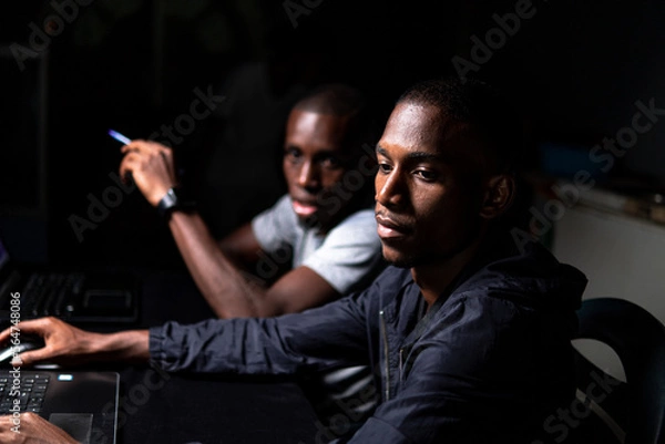 Obraz Two black males looking at computer screen in dark room
