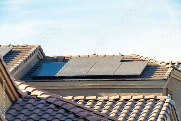 Obraz Solar pannels or photovoltaic generators on suburban rooftop in late afternoon sun in neighborhood in urban area of city
