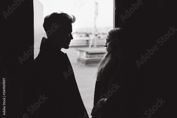 Fototapeta Beautiful stylish and fashionable couple in a suit, dress and coat with gloves on a classic photo shoot in a photo studio and on the street, where they look at each other, hold hands and hug.