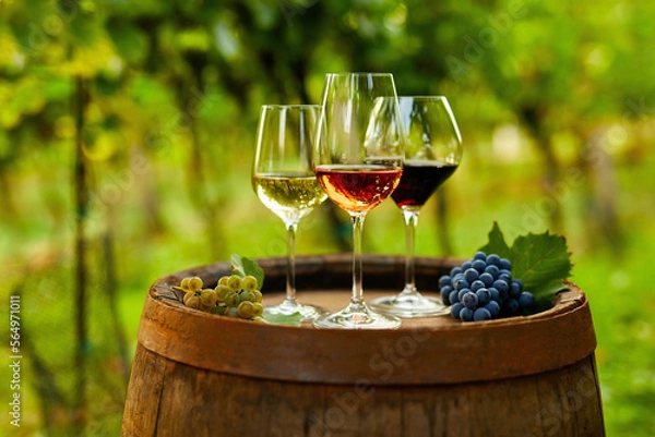 Obraz Three glasses of wine on an old wooden barrel with grapes