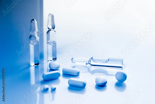 Obraz multivitamin pills and vaccine ampoules close-up