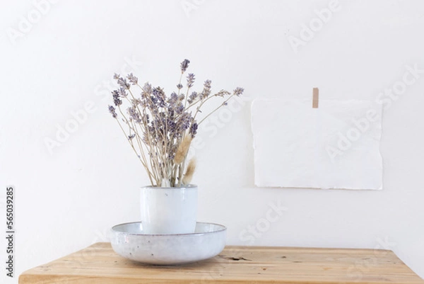 Obraz Modern ceramic vase with Lavender flowers, on a vintage bench, table, and blank paper on the wall background. Scandinavian interior.