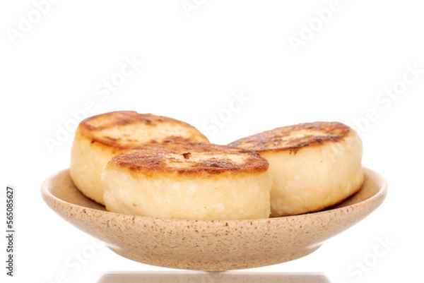 Fototapeta Three homemade cheese pancakes on a ceramic saucer, macro, isolated on a white background.