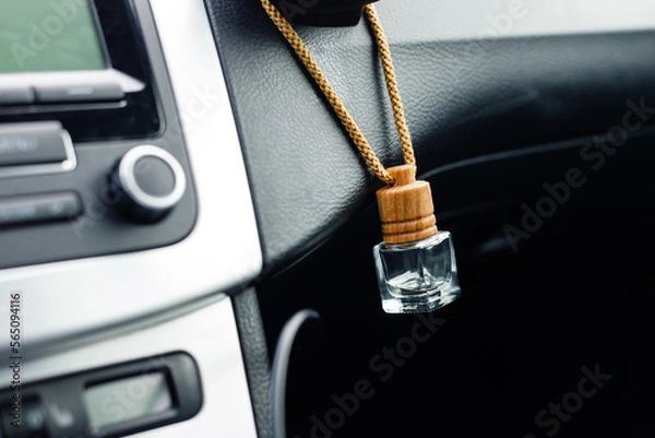 Fototapeta Small aroma glass jar car air freshener hanging on dashboard in vehicle saloon.