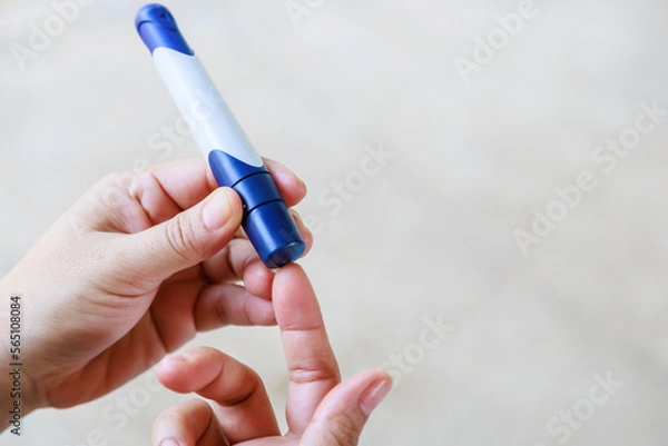 Obraz Close up of woman hands using lancet on finger to check blood sugar level by Glucose meter using as Medicine, diabetes, glycemia, health care and people concept.