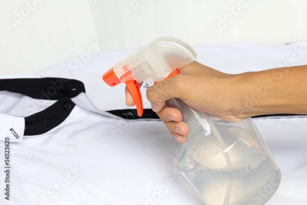 Obraz Spraying a shirt with laundry detergent in spray bottle.