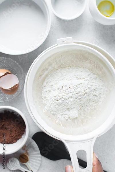 Fototapeta Sifting flour for baking, a plastic sieve with flour in it
