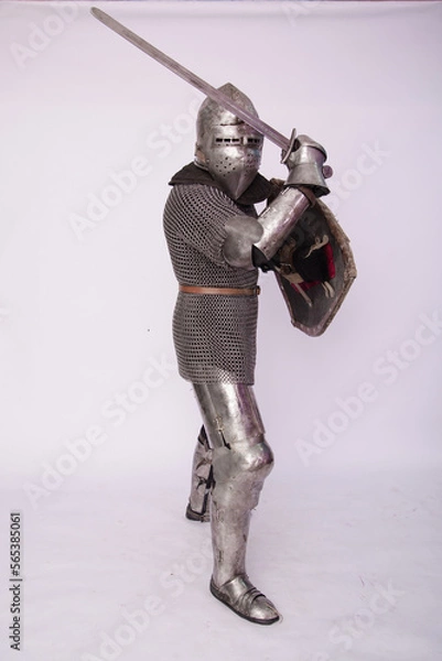 Fototapeta Romantic knight in armor with sword and helmet. Warrior in chain mail on a white background.