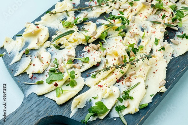 Obraz Wooden board with butter and herbs with seeds smeared on it, close-up.