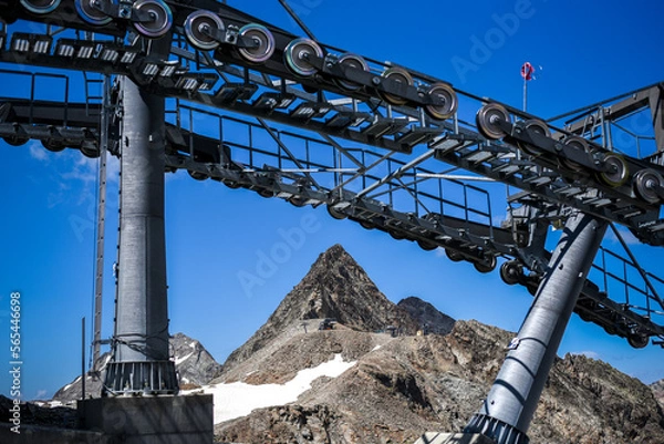 Fototapeta Gondola cables and engine with mountain in between