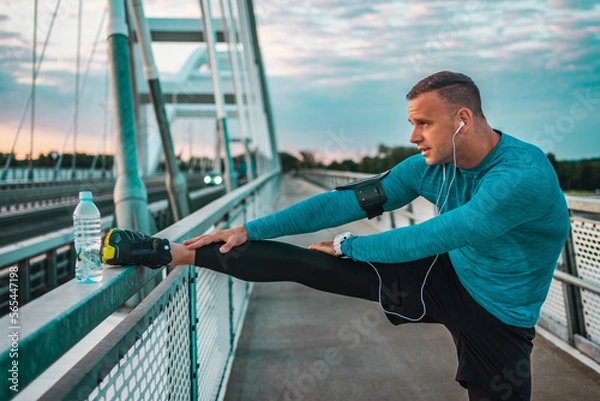 Fototapeta A man have a Training at the bridge, stretching muscles and exercising. Athlete person.