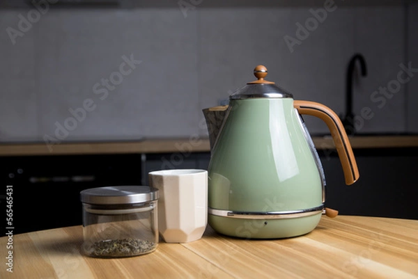 Fototapeta stylish teapot, cup and green tea stand on a wooden table in the kitchen