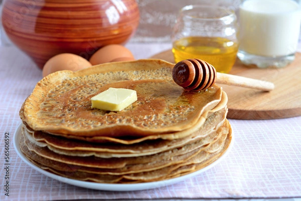 Fototapeta hot fried pancakes on plate on rustic table with honey dipper, ceramic pot and cutting board