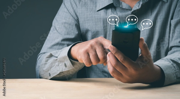 Fototapeta Man hand using smartphone typing Live chat chatting and social network concepts, chatting conversation working at home in chat box icons pop up. Social media marketing technology concept.