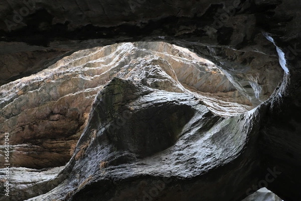 Fototapeta Bizarre shapes in a dark mountain gorge - with layers illuminated by the sun.