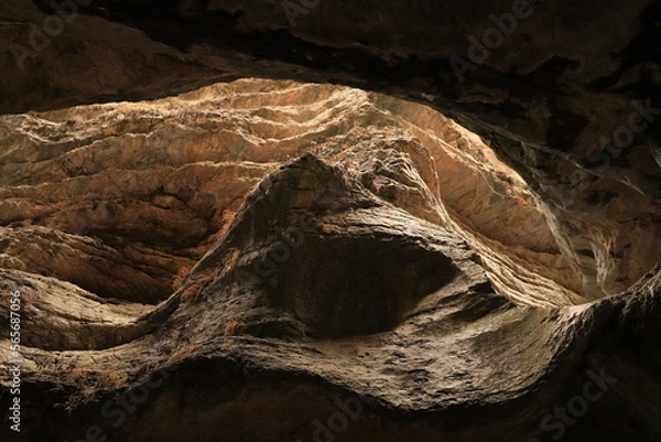 Fototapeta Bizarre shapes in a dark mountain gorge - with layers illuminated by the sun.