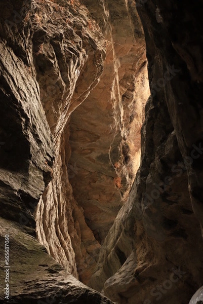 Fototapeta Bizarre shapes in a dark mountain gorge - with layers illuminated by the sun.