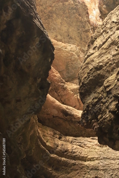 Fototapeta Bizarre shapes in a dark mountain gorge - with layers illuminated by the sun.