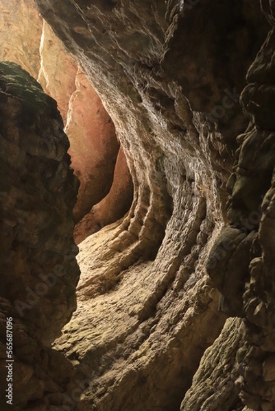 Fototapeta Bizarre shapes in a dark mountain gorge - with layers illuminated by the sun.